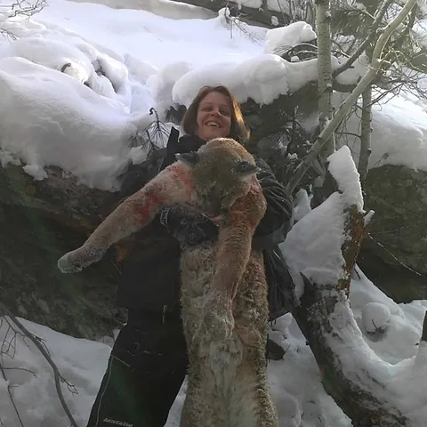 Hunter holding a mountain lion in deep snow