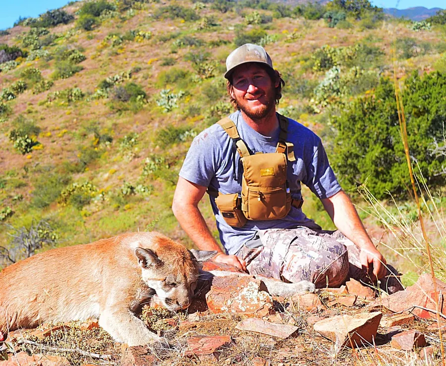 Hunter with a mountain lion on a dry desert hillside
