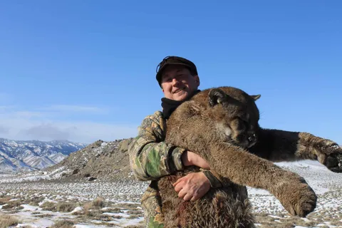 Hunter with a mountain lion in open snowy country