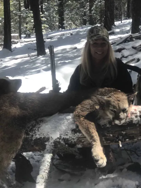 Hunter with a mountain lion on a snowy log